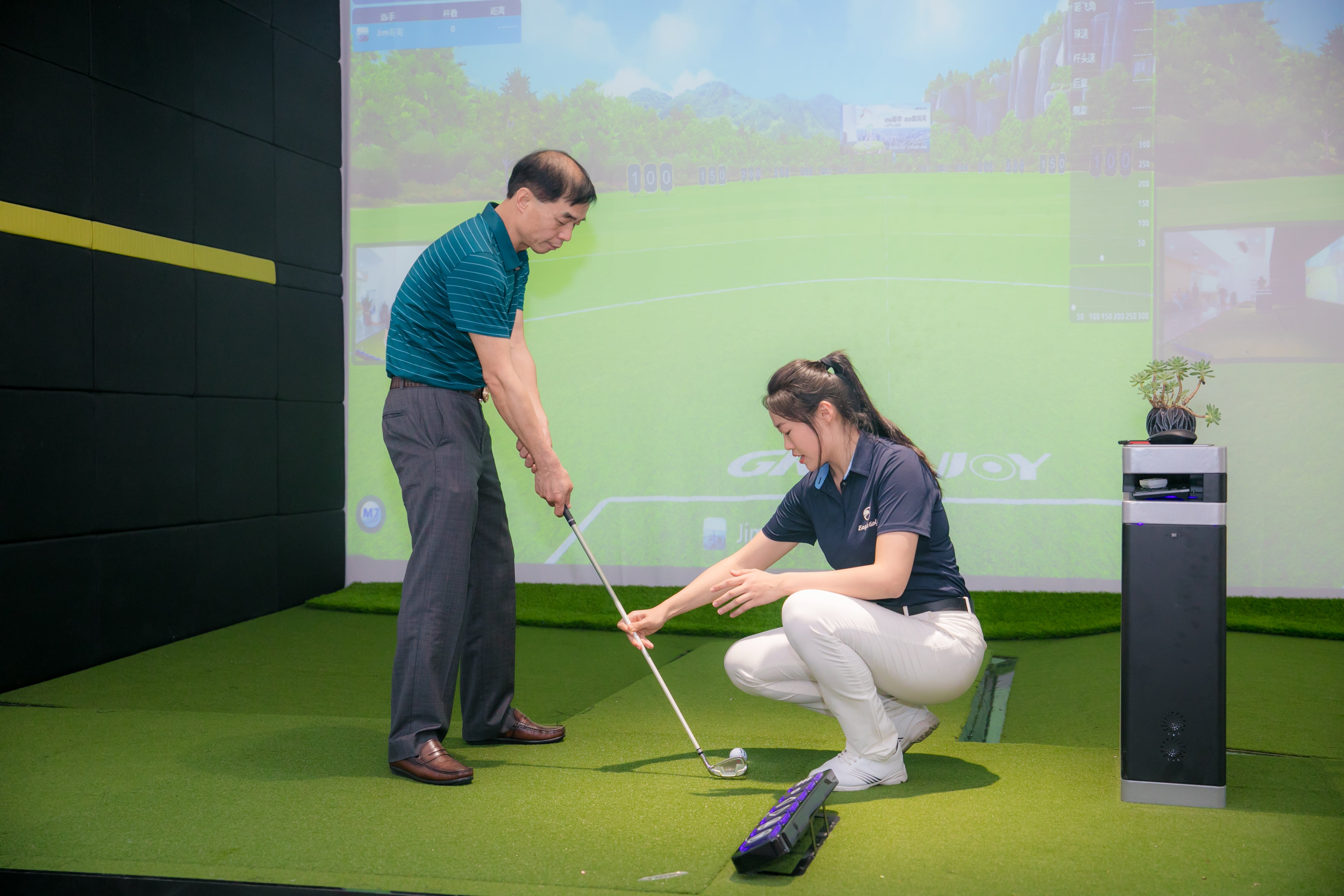 Two people practicing golf swings in a simulator room.